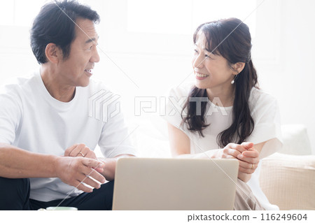 A couple in their 50s looking at a computer in a bright and beautiful living room 116249604