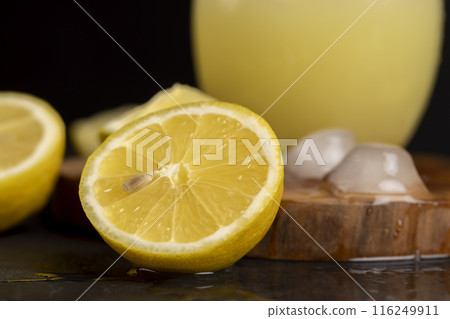 a close-up of lemons and a glass of lemon natural juice 116249911