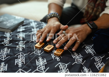 Fortune teller arrange wooden runes on a table covered with a mystical cloth. Forecasting and divination concept 116251862
