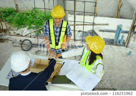 Overhead view of contractor and architect team stacking hands together at construction site 116251962