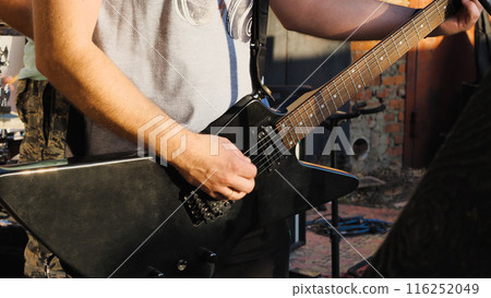 A person's body is visible as they passionately play an electric guitar, embodying musical talent and rock and roll spirit. 116252049