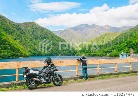 A rider looking at the lake he visited on a motorcycle 116254472