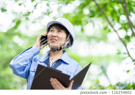 Woman in work clothes, fresh greenery, helmet, smartphone 116254601