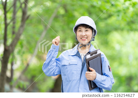 Women in work clothes, fresh green helmet, tablet Women in work clothes, fresh green helmet, tablet 116254627