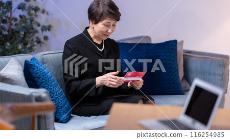 Woman in mourning clothes looking at bankbook Woman in mourning clothes looking at bankbook 116254985