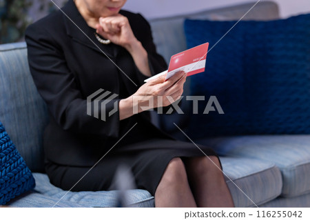 Woman in mourning clothes looking at bankbook, no face Woman in mourning clothes looking at bankbook, no face 116255042