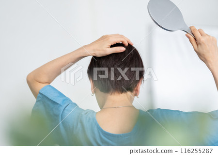 Woman putting on a wig, hair care, back view 116255287