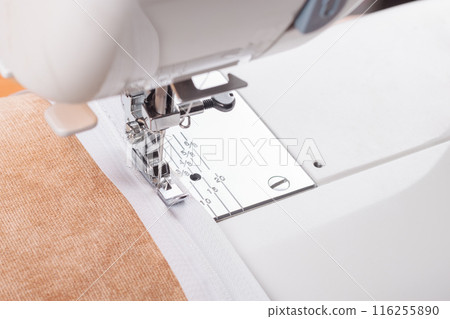 Modern sewing machine special presser foot with beige fabric and zipper, closeup Modern sewing machine special presser foot with beige fabric and zipper, closeup 116255890