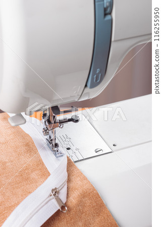 Modern sewing machine special presser foot with beige fabric and zipper, closeup Modern sewing machine special presser foot with beige fabric and zipper, closeup 116255950