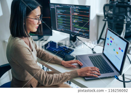 Asian prompt engineer develop coding app with software data sitting in front of computer monitor at office Asian prompt engineer develop coding app with software data sitting in front of computer monitor at office 116256092