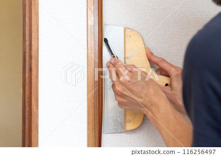 A craftsman replacing wallpaper on a house 116256497
