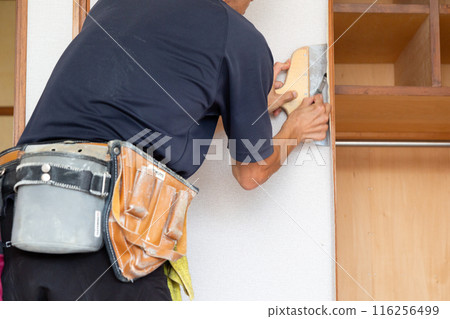 A craftsman replacing wallpaper on a house 116256499