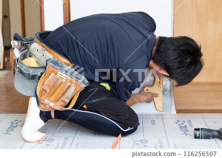 A craftsman replacing wallpaper on a house 116256507