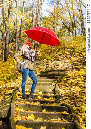 Woman walking in park with umbrella 116257447