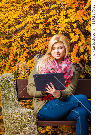Woman relaxing sitting on bench in park using tablet Woman relaxing sitting on bench in park using tablet 116257552