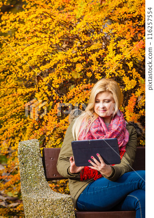 Woman relaxing sitting on bench in park using tablet Woman relaxing sitting on bench in park using tablet 116257554