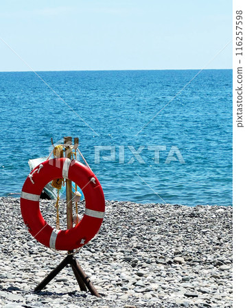 Lifebuoy on the seashore. Beach safety equipment. Positioned by water s edge for emergencies and rescue purposes Lifebuoy on the seashore. Beach safety equipment. Positioned by water s edge for emergencies and rescue purposes 116257598