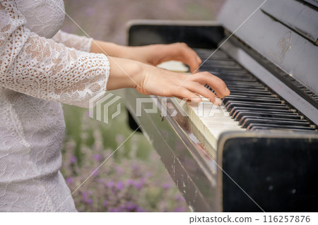A woman is playing the piano in a field of purple flowers A woman is playing the piano in a field of purple flowers 116257876