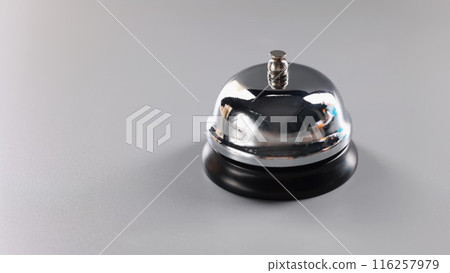 Silver bell stands on grey surface to attract attention, press bell to call for service Silver bell stands on grey surface to attract attention, press bell to call for service 116257979