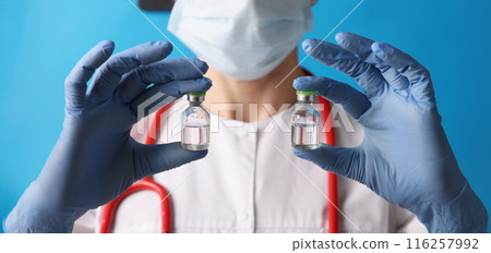 Scientist holding two bottles with injection in blue gloves 116257992