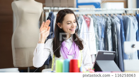 Woman fashion stylist greets customer remotely on tablet 116258063