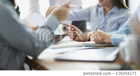 Coworkers discussing working moments and checking financial report in conference room 116258171