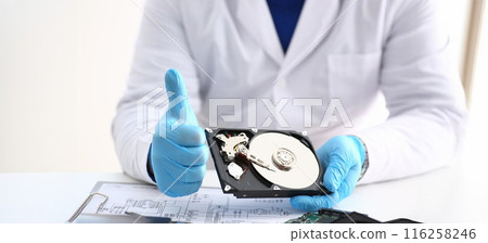 Man in uniform hold disassembled hard drive from computer, hdd and reader, show thumbs up 116258246
