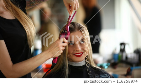 Blonde female on hairdresser appointment, master create curly hairstyle 116258974