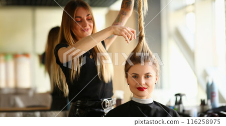 Hairdresser holding long lock of hair and going to cut length with scissors Hairdresser holding long lock of hair and going to cut length with scissors 116258975