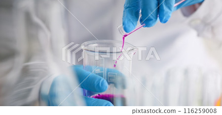 Scientist pour pink liquid from flask in medical chemistry laboratory Scientist pour pink liquid from flask in medical chemistry laboratory 116259008