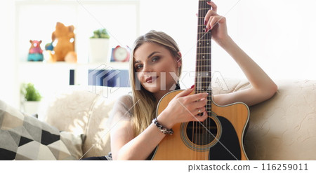 Young pretty woman playing on guitar, talented artist spend free time learning new song on musical instrument Young pretty woman playing on guitar, talented artist spend free time learning new song on musical instrument 116259011
