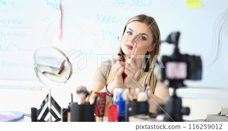 Pretty young woman wear makeup, glamour blonde woman visagist show lipstick on camera 116259012