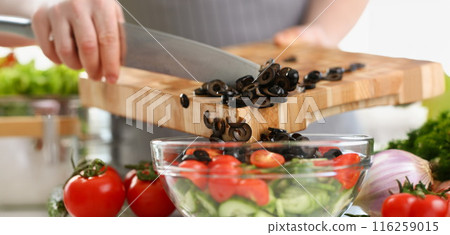 Man chef cutting olives, ripe vegetable ingredient for fresh spring salad Man chef cutting olives, ripe vegetable ingredient for fresh spring salad 116259015