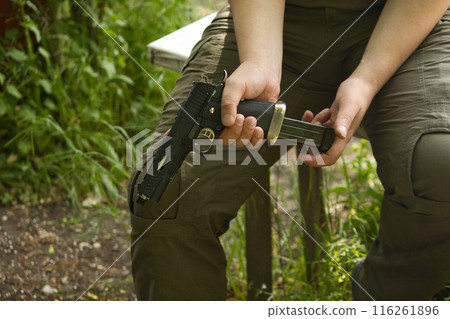 someone in green pants is sitting with a gun in his hands on the street someone in green pants is sitting with a gun in his hands on the street 116261896