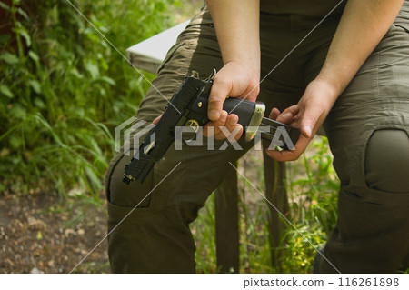 someone in green pants is sitting with a gun in his hands on the street someone in green pants is sitting with a gun in his hands on the street 116261898