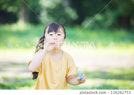 Elementary school girl playing with soap bubble Elementary school girl playing with soap bubble 116262753