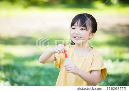 Elementary school girl playing with soap bubble 116262755