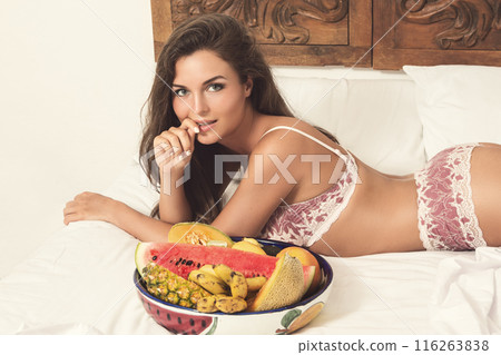 Beautiful woman and bowl with sweet fruits in the bed Beautiful woman and bowl with sweet fruits in the bed 116263838