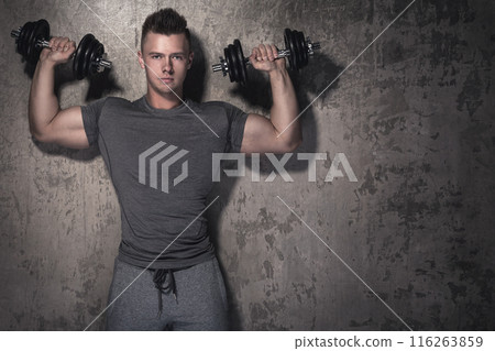 Young bodybuilder is doing overhead press exercise 116263859