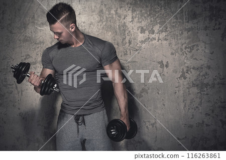 Young bodybuilder doing biceps curls with dumbbells Young bodybuilder doing biceps curls with dumbbells 116263861