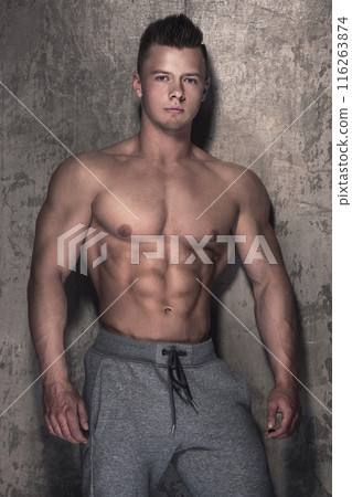 Handsome and muscular guy against concrete wall 116263874