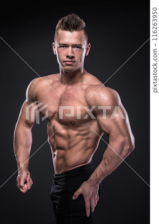 Young bodybuilder is showing his muscles in studio 116263950