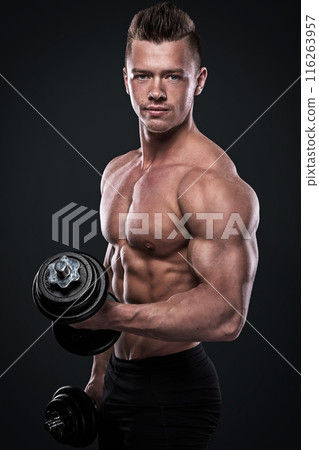 Young man bodybuilder doing exercises with dumbbells Young man bodybuilder doing exercises with dumbbells 116263957