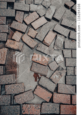 Wet pavement after rain, vertical. Broken paving stones with puddle. Wet brick pavers. Street walkway close up. Old paving slabs background. Urban sidewalk. Autumn mood in the city. Wet pavement after rain, vertical. Broken paving stones with puddle. Wet brick pavers. Street walkway close up. Old paving slabs background. Urban sidewalk. Autumn mood in the city. 116264108