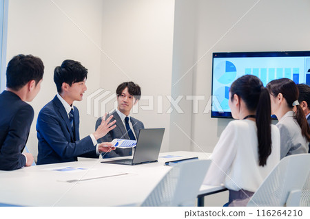 A young man wearing a suit speaking at a meeting 116264210