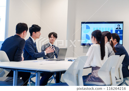 A young man wearing a suit speaking at a meeting 116264216