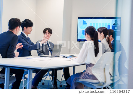 A young man wearing a suit speaking at a meeting 116264217