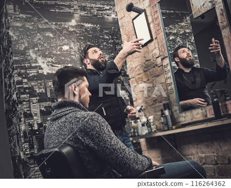 Barber during his work with client in his studio 116264362
