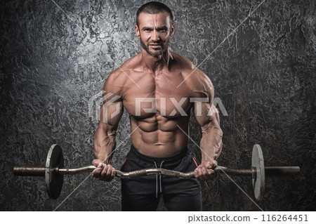 Bodybuilder man with barbell against concrete wall 116264451