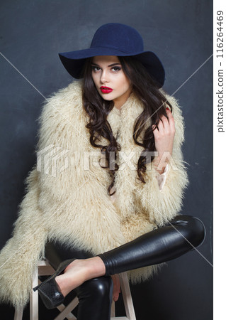 Stylish young brunette lady with makeup and long curly hair posing Stylish young brunette lady with makeup and long curly hair posing 116264469